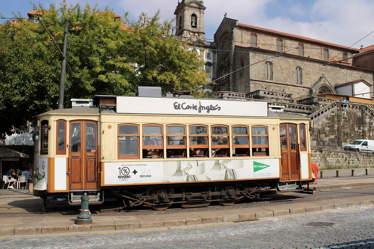 A vintage Porto tram passing old stone churches